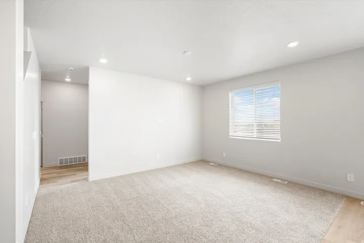 **DISCLAIMER** Interior package may vary. Recessed lighting, light-toned carpeting, wood-finish flooring, white walls, and a window with horizontal blinds