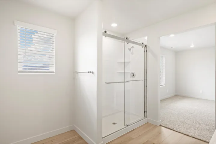 **DISCLAIMER** Interior package may vary. Glass-enclosed shower with a chrome fixture, recessed lighting, and wood-finish flooring