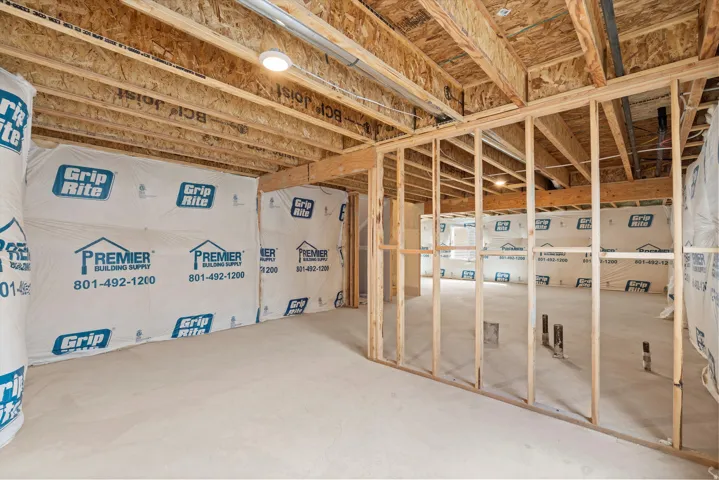 Unfinished basement featuring wood framing, exposed joists, and concrete flooring