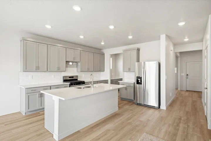 **DISCLAIMER** Interior package may vary. Modern kitchen featuring light gray cabinetry, stainless steel appliances, white subway tile backsplash, and wood-finish flooring