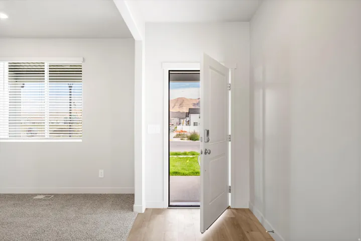 **DISCLAIMER** Interior package may vary. Entryway featuring wood-finish flooring, a white paneled door, and a large window with white blinds