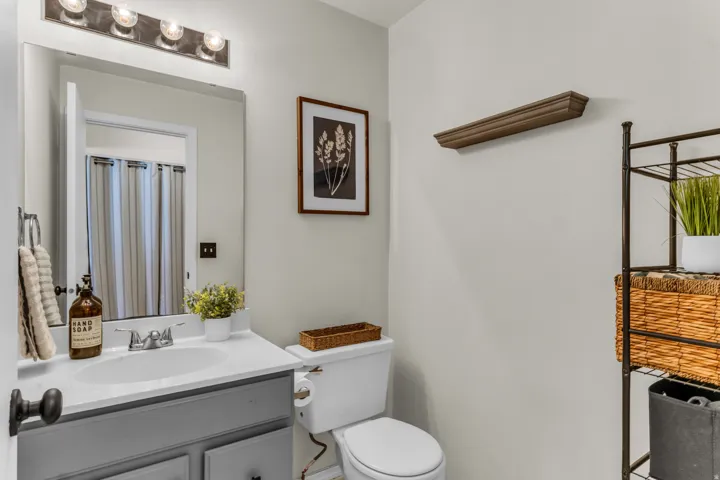 Elegant bathroom featuring a gray vanity with white countertop, chrome fixtures, and large framed mirror with integrated lighting