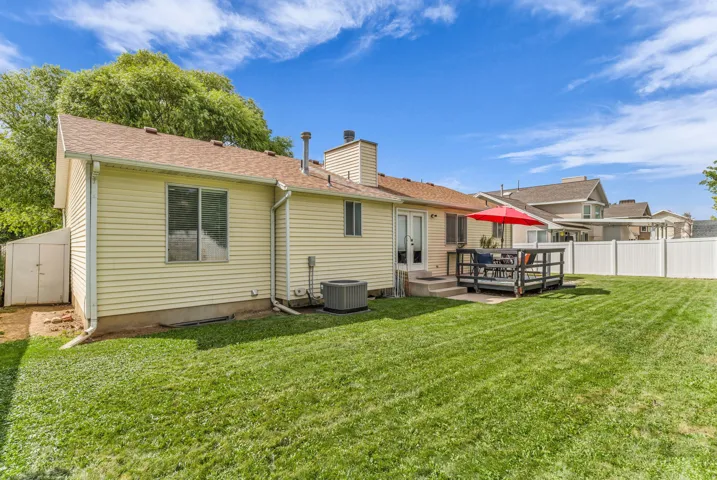 Expansive lawn area with a white privacy fence, a wood deck, and a utility shed