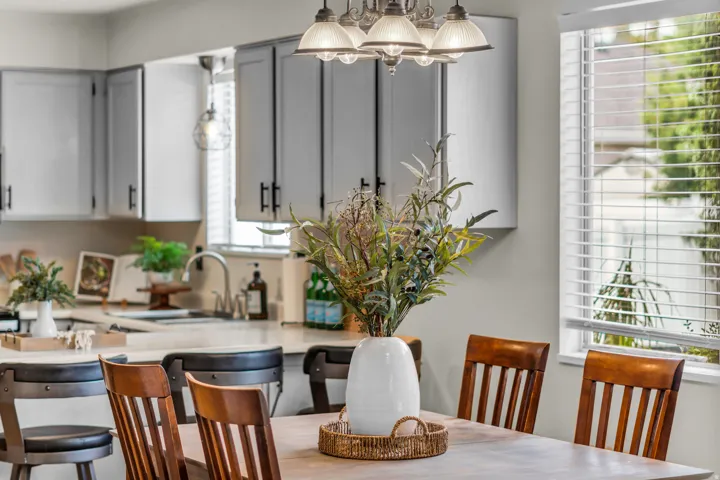 Recessed lighting, wood-finish dining table, chandelier, and a window with horizontal blinds
