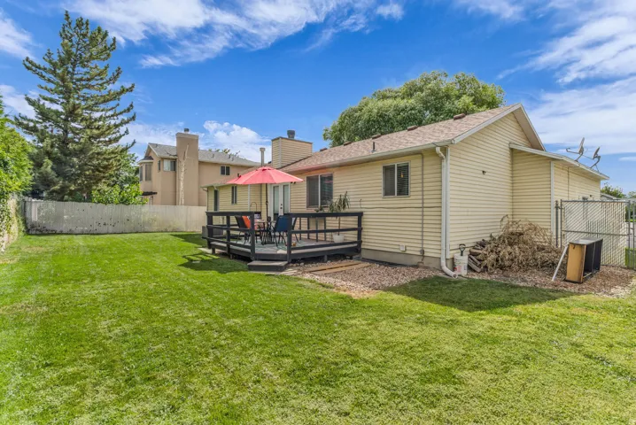 Expansive grassy yard with a multi-level wood deck and chain-link fencing