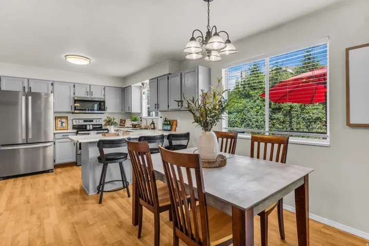 Kitchen featuring wood-finish flooring, stainless steel appliances, gray cabinetry, and a center island with counter seating