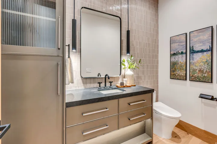 Floating vanity with dark countertop, rectangular mirror, and two pendant light fixtures