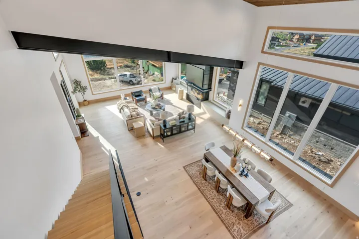 Open-concept floor plan featuring light wood-finish flooring, a contemporary fireplace, and a dining area with a linear chandelier