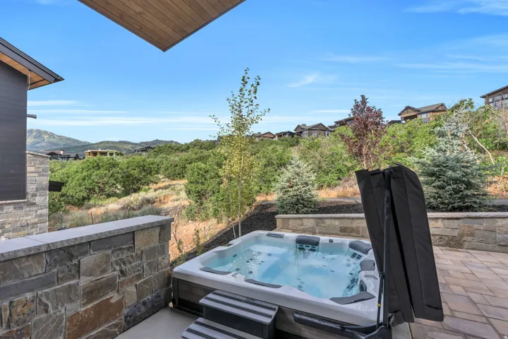 Outdoor spa with integrated steps, stone retaining wall, and paver patio