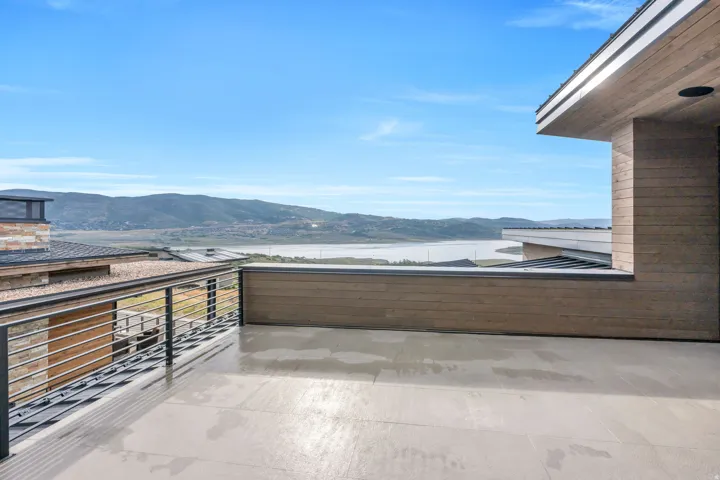 Expansive outdoor patio with a cable railing system, offering panoramic mountain and water scenery