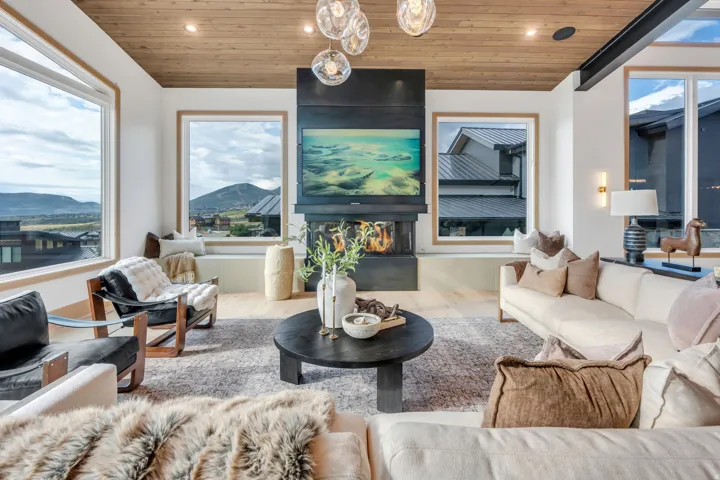 Expansive windows, wood-finish ceiling, built-in fireplace, recessed lighting, and wall-mounted sconces
