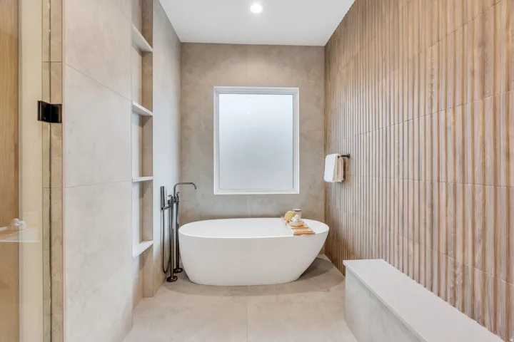 Freestanding bathtub with floor-mounted faucet, frosted window, recessed ceiling lighting, and built-in wall shelving
