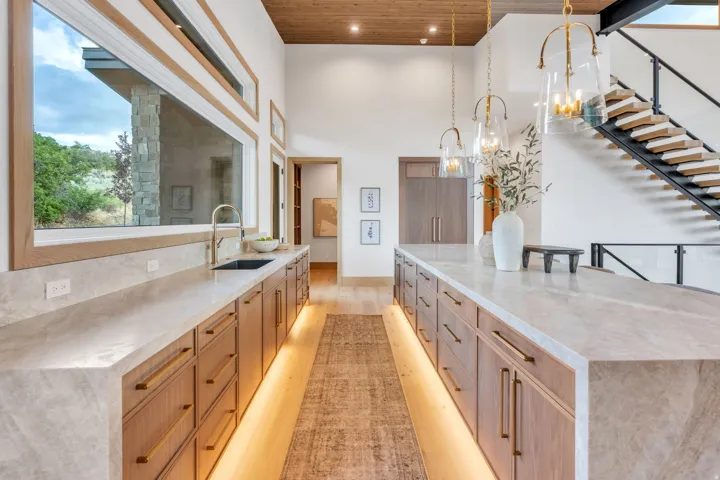 High ceilings, wood-finish flooring, linear window bank, undermount sink, and integrated cabinet lighting