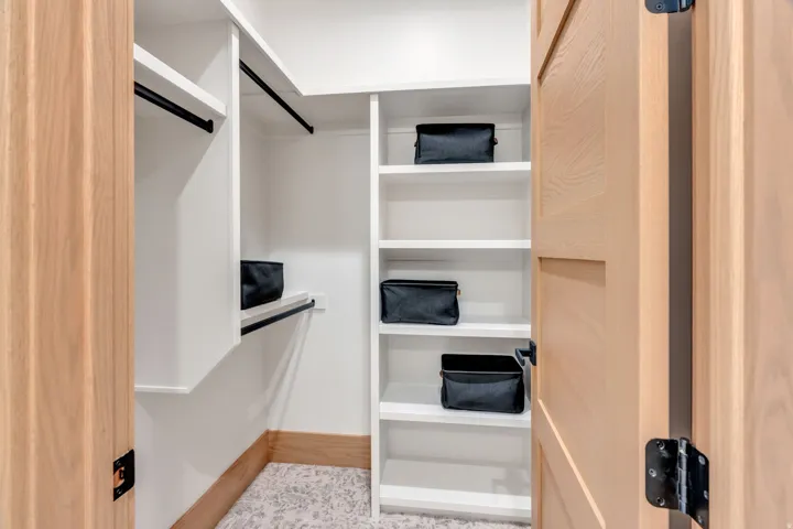 Custom closet system featuring white shelving and black hanging rods