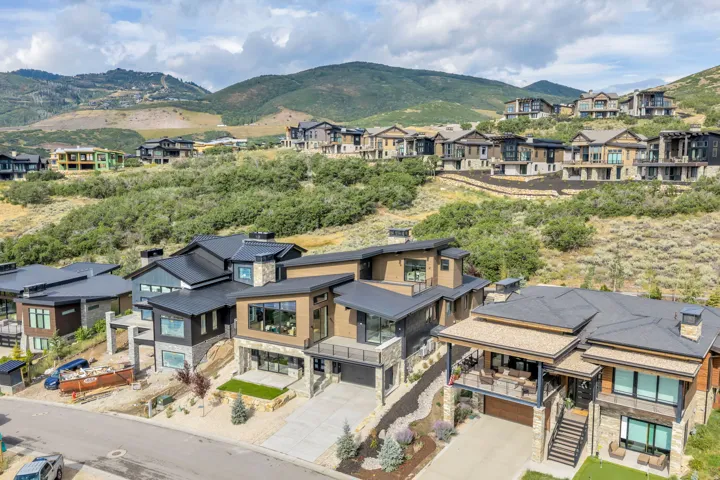 Modern residential architecture featuring flat and pitched roofs, stone and wood-finish exteriors, and multiple balconies
