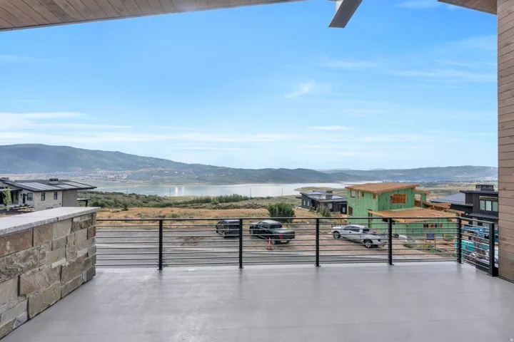 Expansive outdoor deck with a stone-clad half-wall, cable railing, and a wood-paneled ceiling