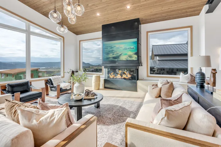 Spacious living area featuring expansive windows, a sleek built-in fireplace, natural wood-finish ceiling, and light wood-finish flooring