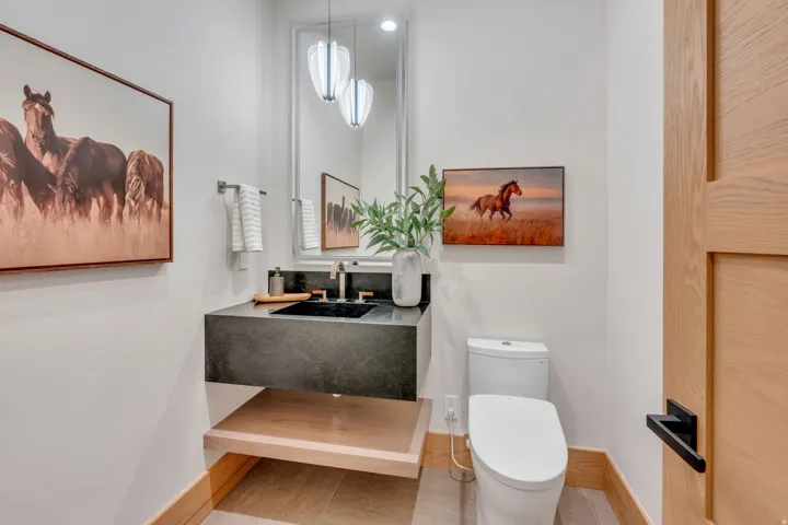 Floating vanity with a dark stone countertop, integrated sink, and modern faucet
