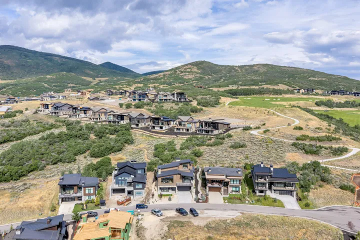 Hillside estate featuring multiple contemporary residences with modern architectural design, expansive manicured grounds, and panoramic mountain backdrop