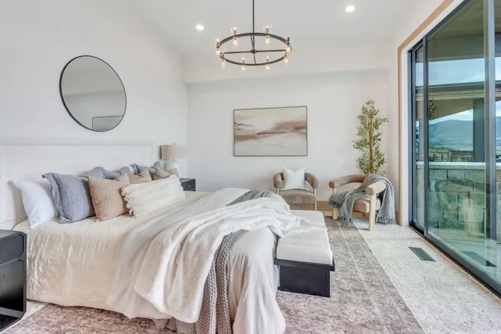 Vaulted ceiling with recessed lighting, large sliding glass doors, contemporary chandelier, wood-finish flooring, and a stone exterior balcony
