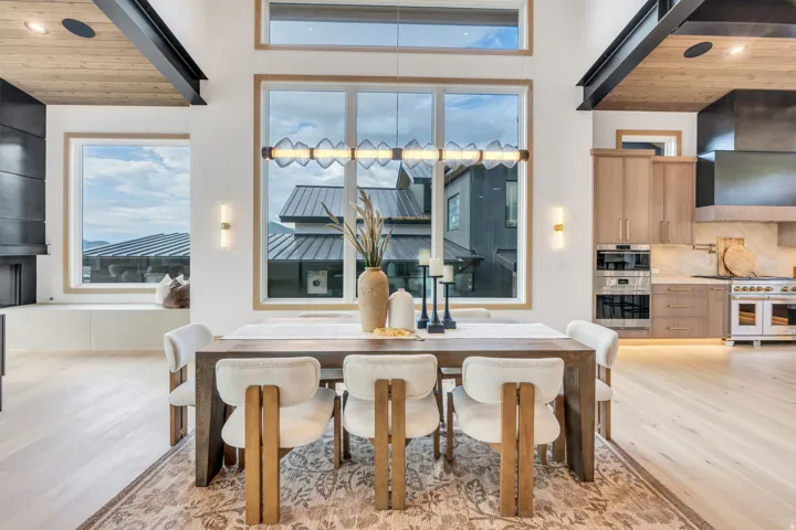 Dining area with wood-finish flooring, a contemporary linear chandelier, and tall windows