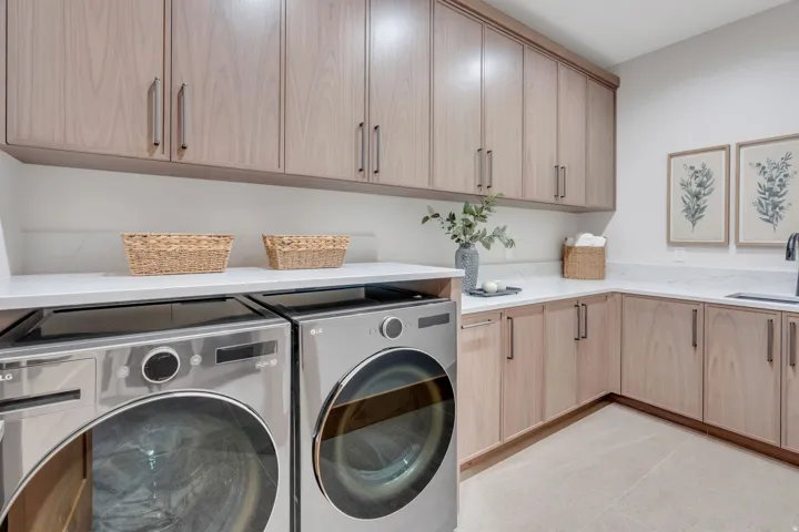 Full-height custom cabinetry with wood-finish doors, solid surface countertops, a built-in sink with a matte black faucet, and light-toned floor tile