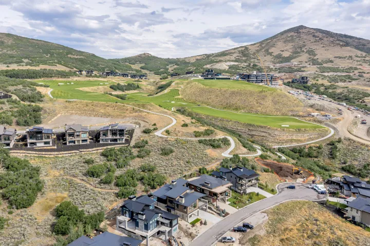 Mountainous terrain with established golf course, winding roads, and residential properties featuring dark roofs