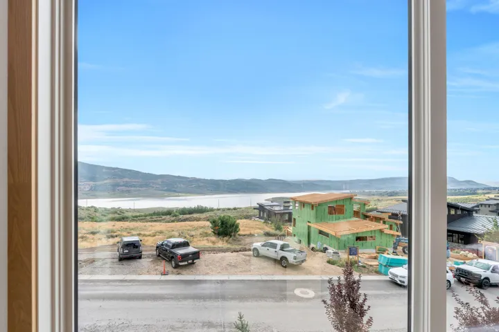 Expansive natural scenery with distant water feature, framed by a large window with white trim