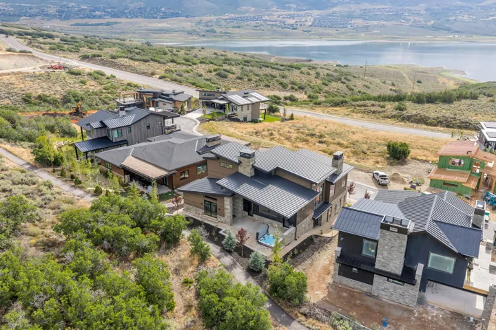 Modern architectural design with multiple structures, dark metal roofing, stone and wood-finish siding, and a prominent chimney