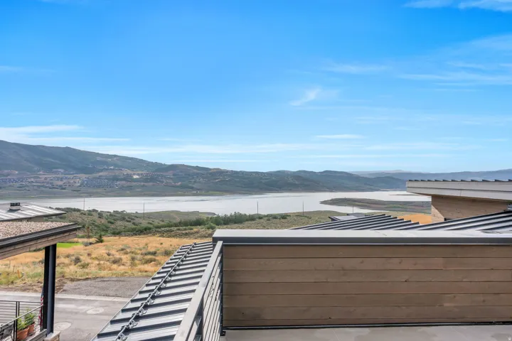 Expansive water and mountain scenery with modern metal roofing and wood-panel exterior accents