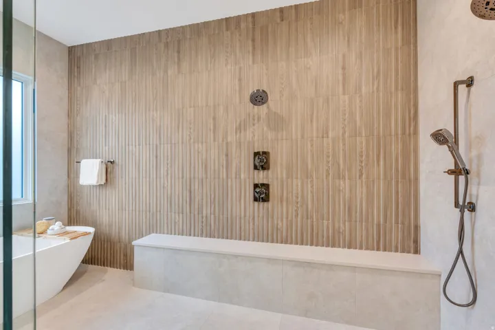 Walk-in shower with a built-in bench, dual shower heads, and an additional handheld shower fixture