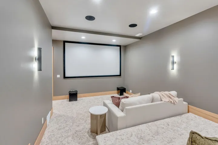 Theater room featuring a large projection screen, recessed lighting, and wall-mounted sconces