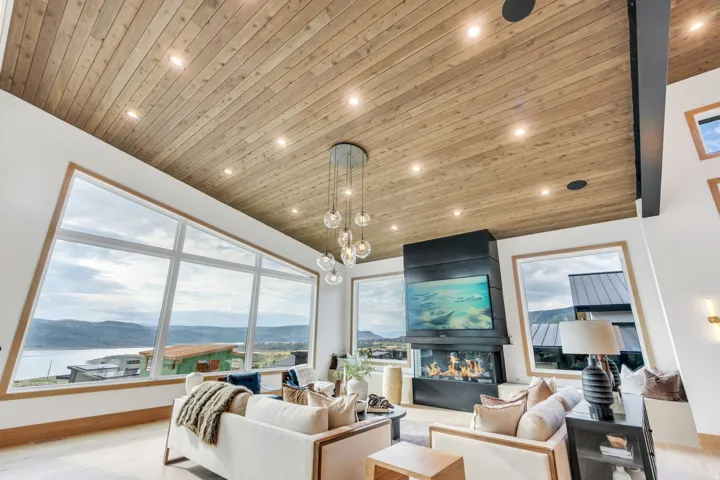 Soaring wood-finish ceiling with recessed lighting and a modern chandelier anchors this light-filled living space