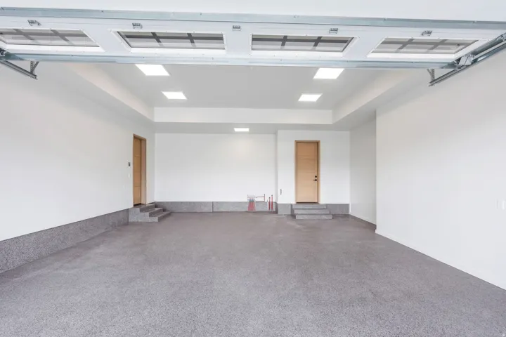 Spacious garage with an epoxy floor finish, recessed ceiling lighting, and a paneled overhead door