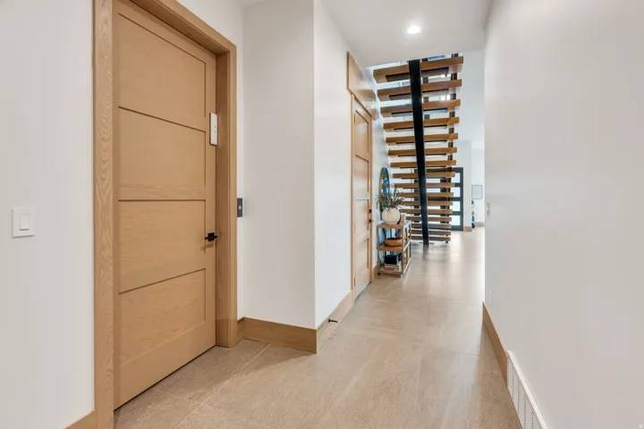 Smooth tile flooring, white walls, light wood-finish doors, and a contemporary open-riser staircase