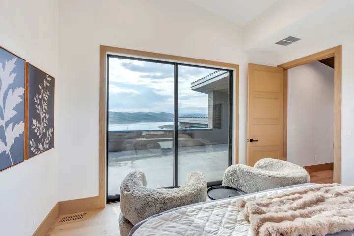 Floor-to-ceiling sliding glass doors with dark frames, wood-finish flooring, light wood-paneled door, and white painted walls
