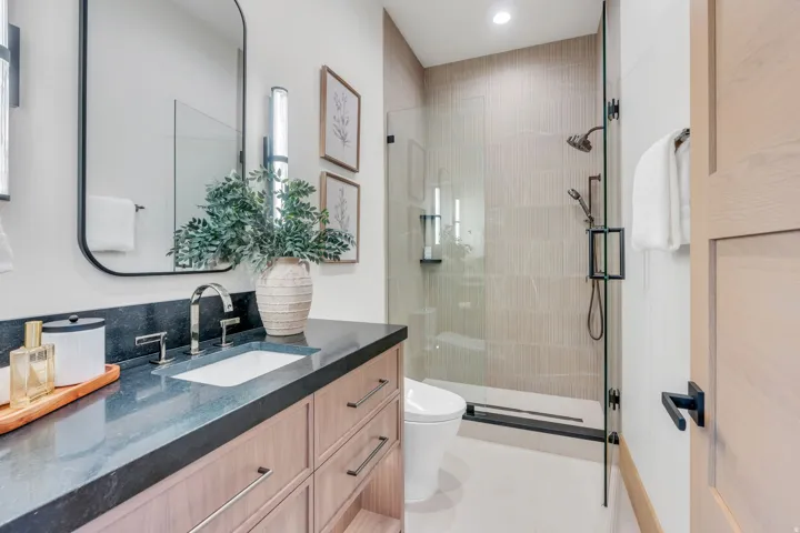 Hardwood-finish vanity with dark countertop, undermount sink, and polished chrome faucet