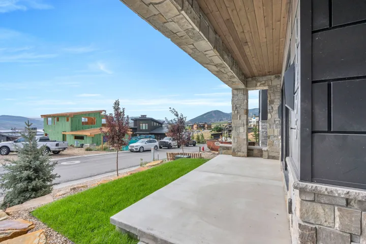 Stone veneer exterior with wood-finish soffit, concrete patio, and a grass lawn