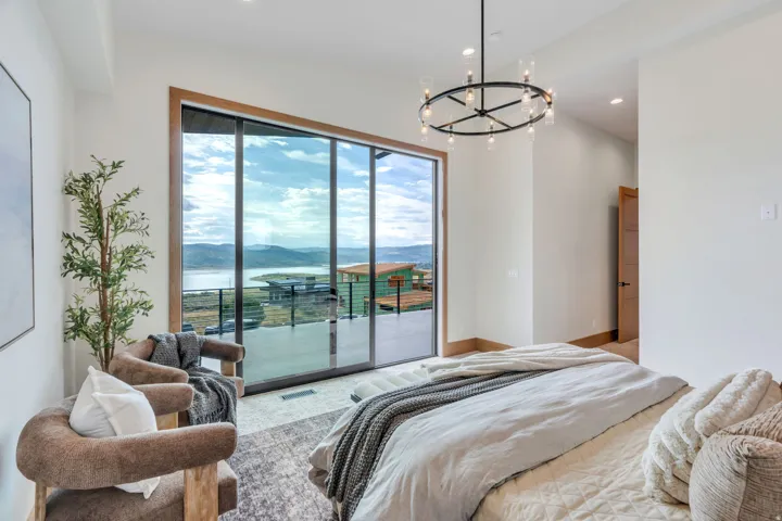 Expansive sliding glass doors, contemporary chandelier lighting, recessed lighting, wood-finish door frames, and a scenic water and mountain backdrop
