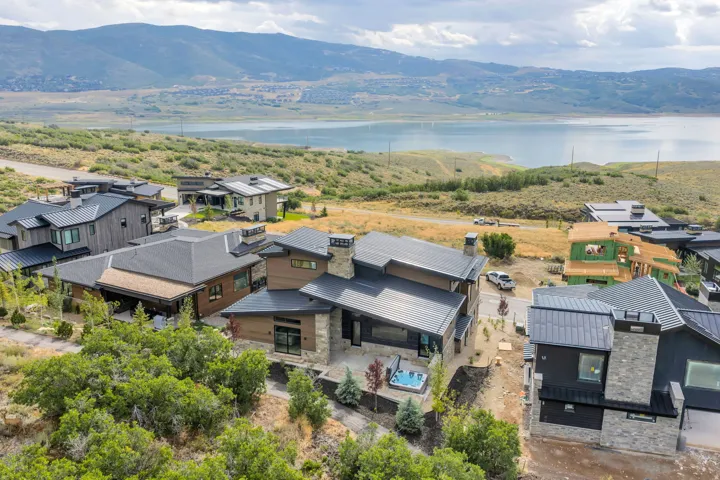 Modern architectural design with a dark metal roof, stone chimney accents, and a built-in outdoor spa