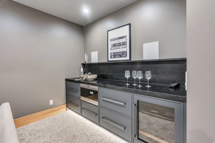 Built-in cabinetry with dark countertops, an integrated microwave, and a beverage cooler