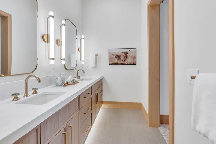 Dual vanity with white countertop, undermount sinks, and brass-finish fixtures