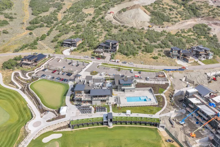Modern residential complex featuring an outdoor swimming pool, multiple outdoor seating areas, and adjacent to a golf course