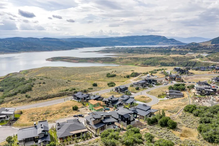 Expansive waterfront scenery, surrounding natural landscape, established neighborhood, modern residences, and winding paved roadways