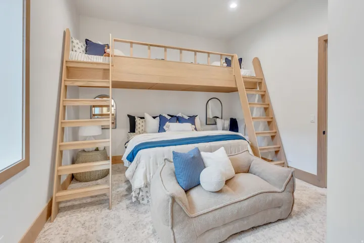 Built-in light wood bunk beds with ladders, recessed lighting, wood-finish door frames, and wall-to-wall patterned carpeting