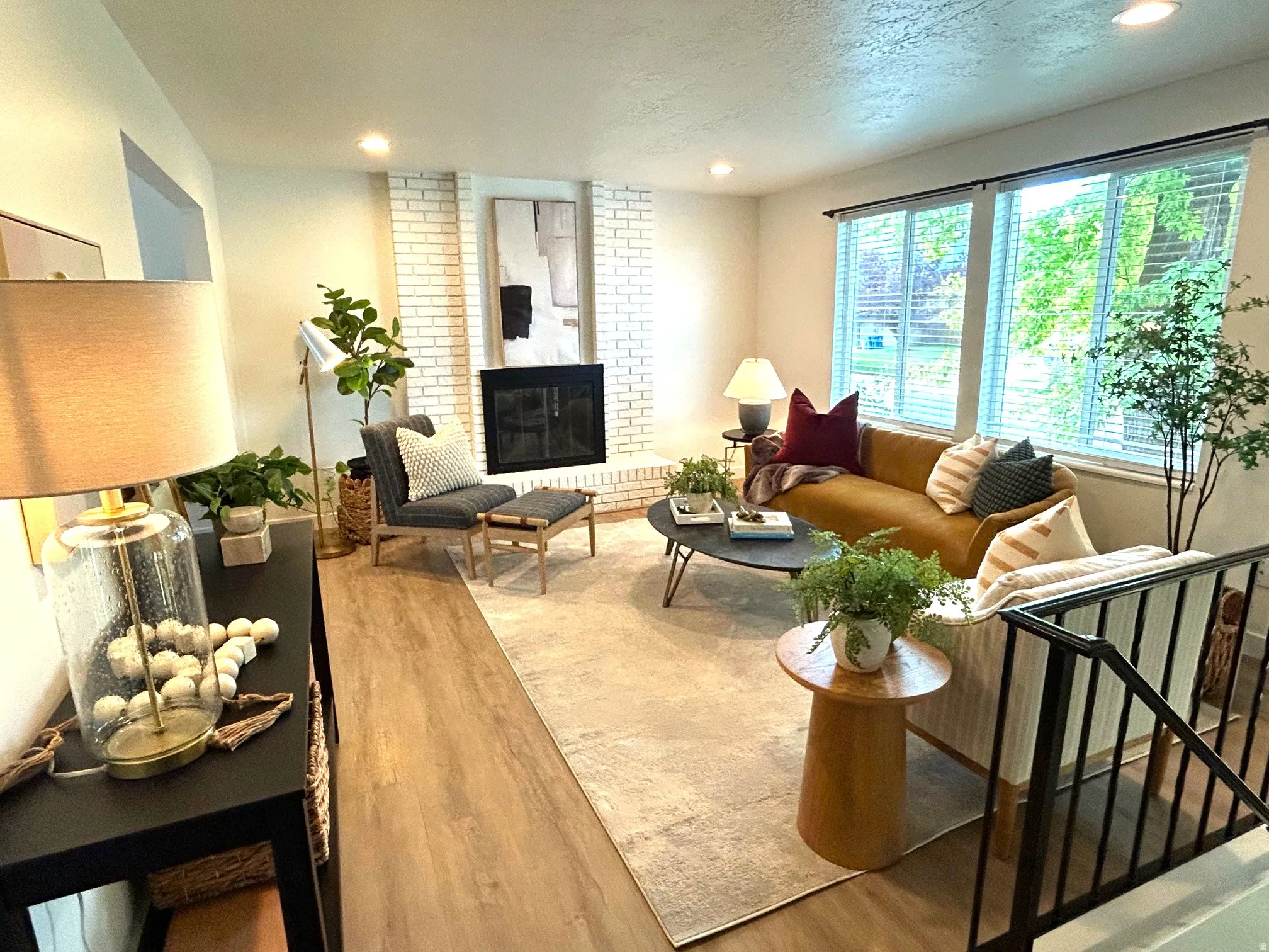 Recessed lighting, wood-finish flooring, white brick-surround fireplace, and large windows