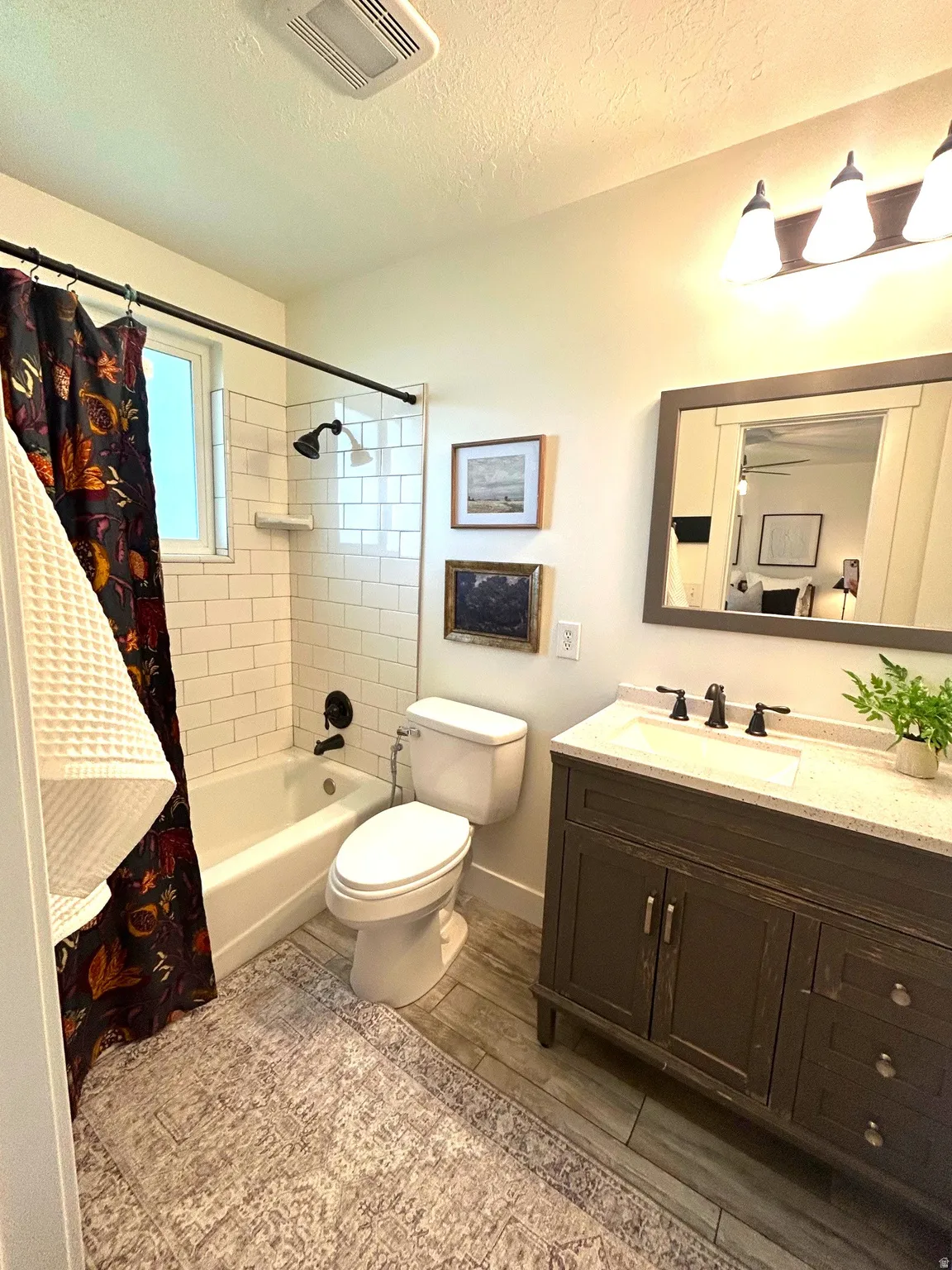 Single vanity with a light countertop, wood-finish flooring, white subway tile shower surround, and a tub/shower combination