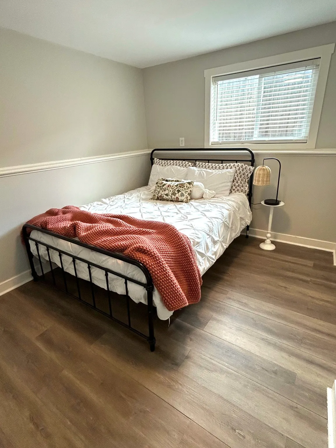 Wood-finish flooring, neutral wall tones, and a window with blinds and white trim