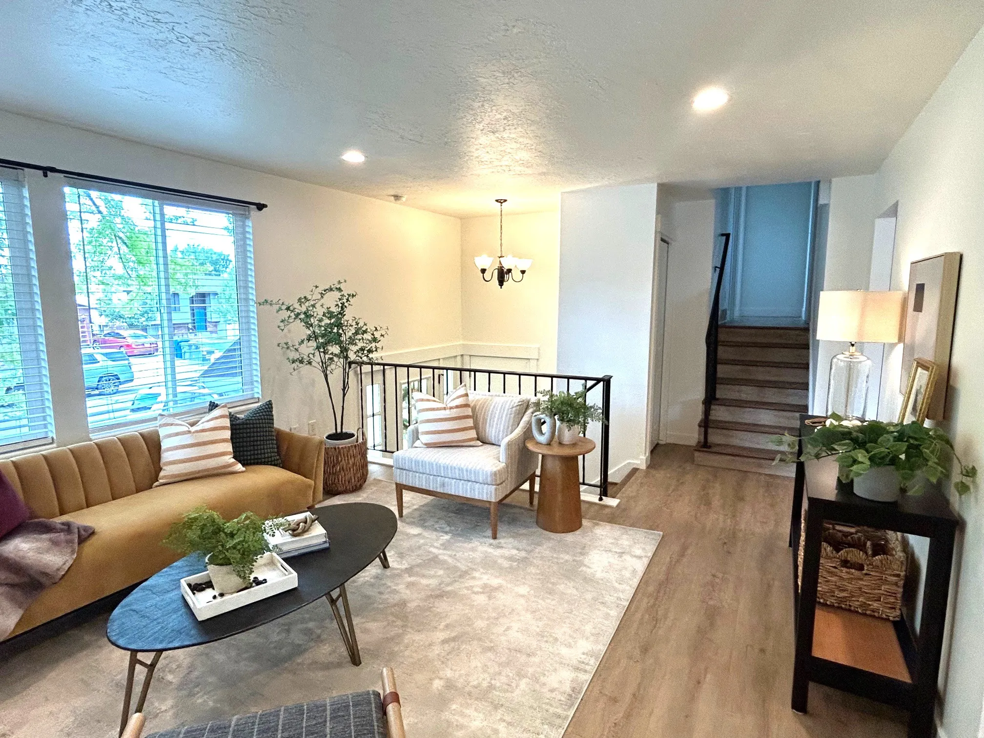 Recessed lighting illuminates wood-finish flooring and a black metal railing