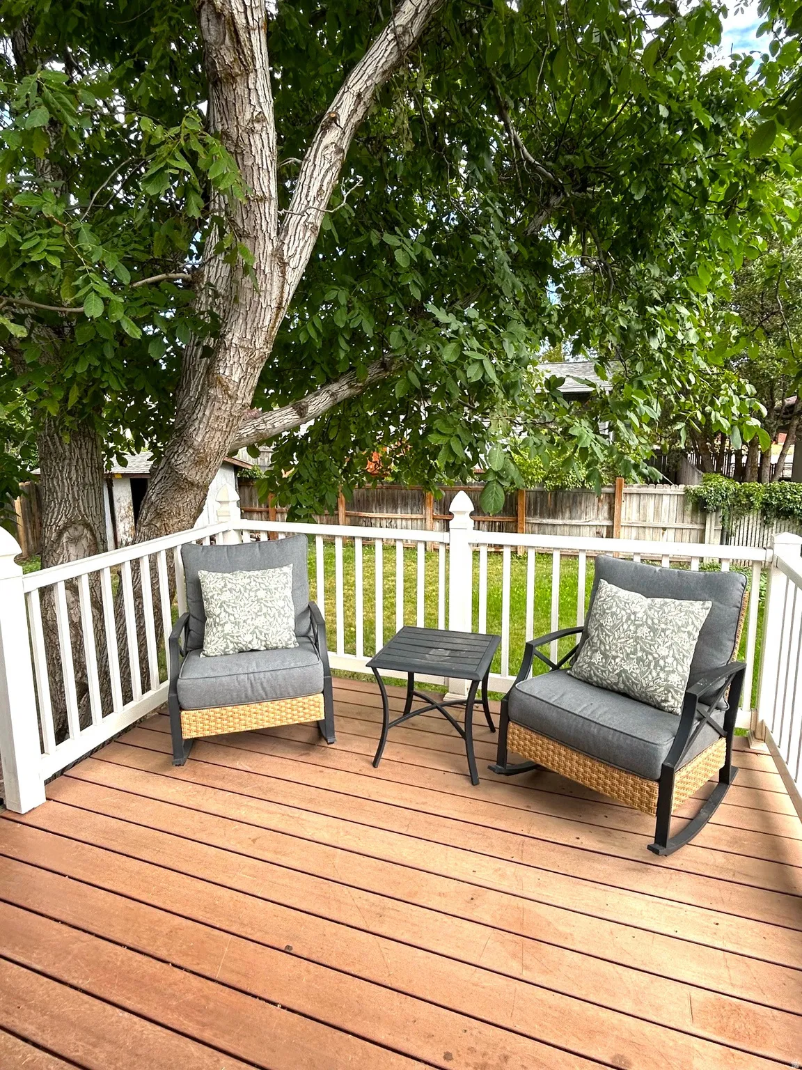 Expansive wood-finish deck with white baluster railing, offering a private outdoor extension